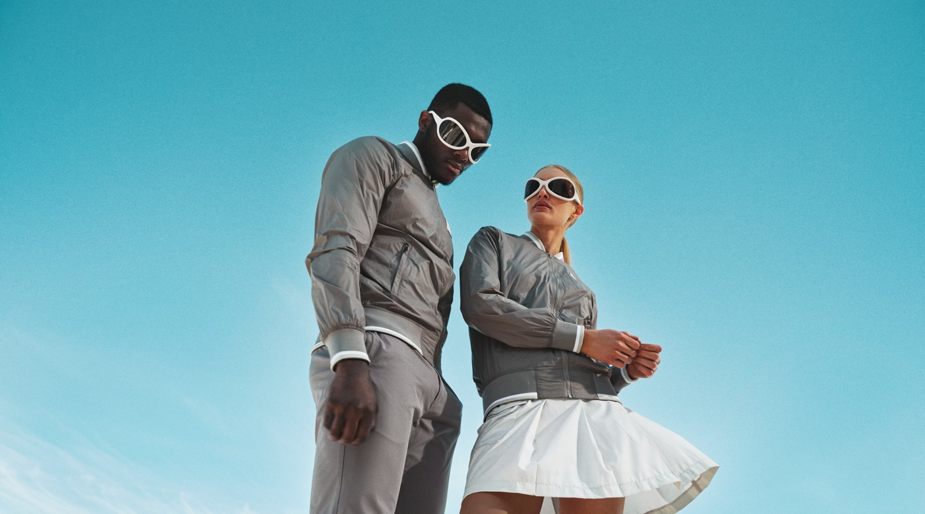 Models posing wearing golf clothes in front of a blue sky.